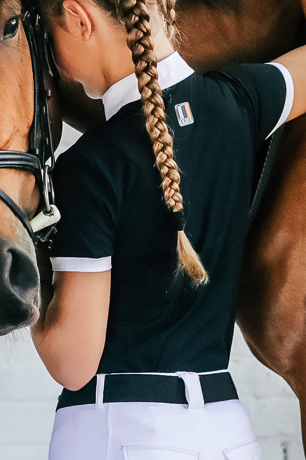 Girl wearing a short sleeve cieli equestrian show shirt in black and white with UV protection and branding detail at the back