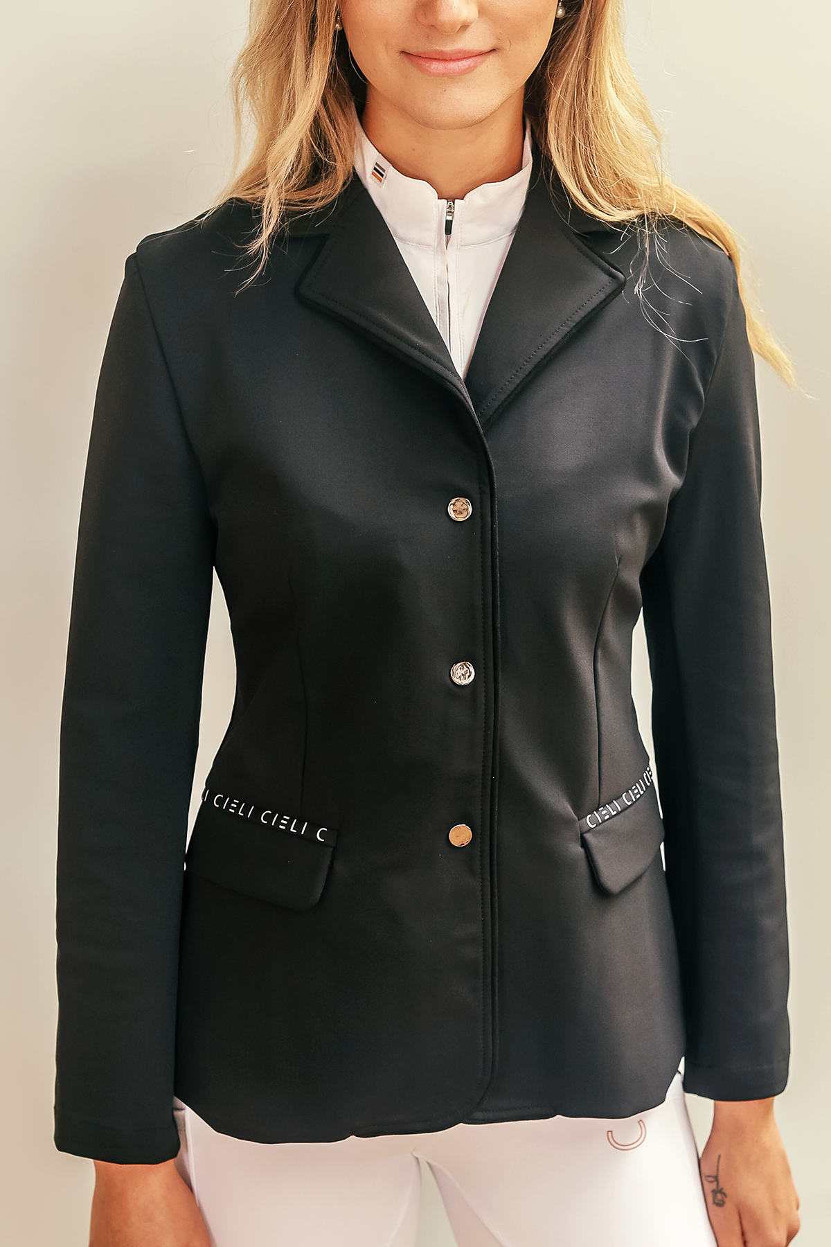 Blonde girl wearing Cieli Equestrian show jacket in black with orange details