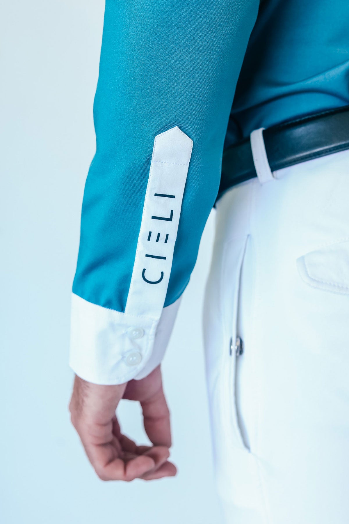 Teal long-sleeve shirt with white cuffs and 'CIELI' branding on a light blue background