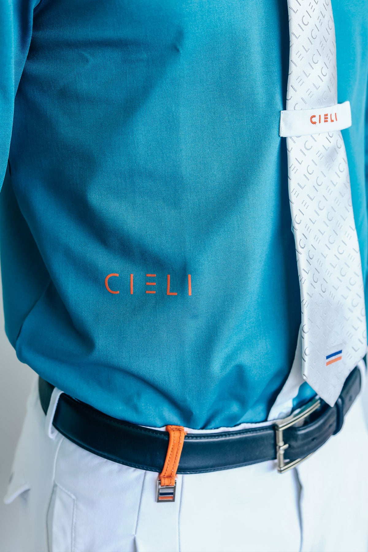 Teal shirt with a white tie and 'CIELI' branding on a gray background