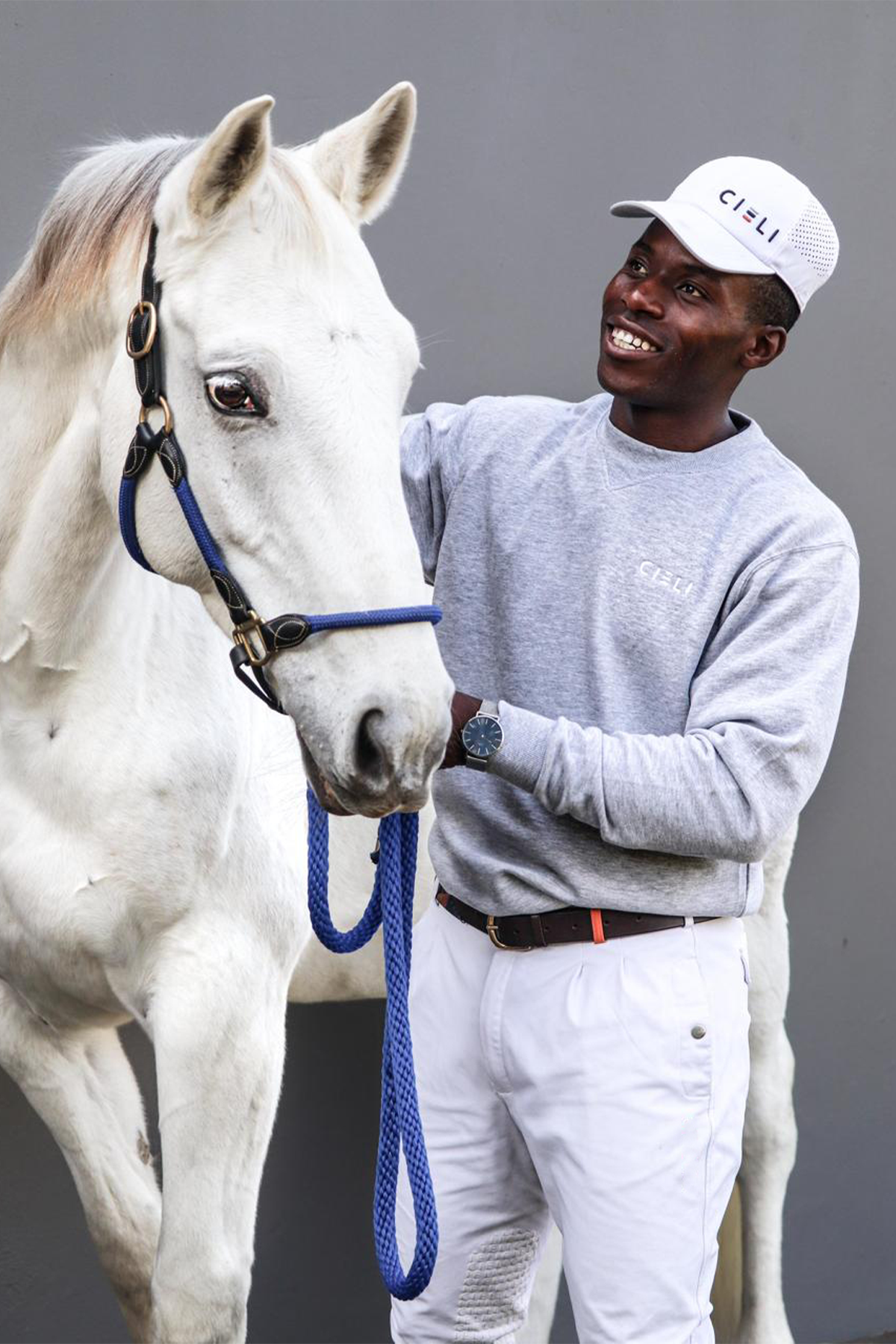 Man wearing a Cieli Equestrian melange grey sweater standing next to a white horse