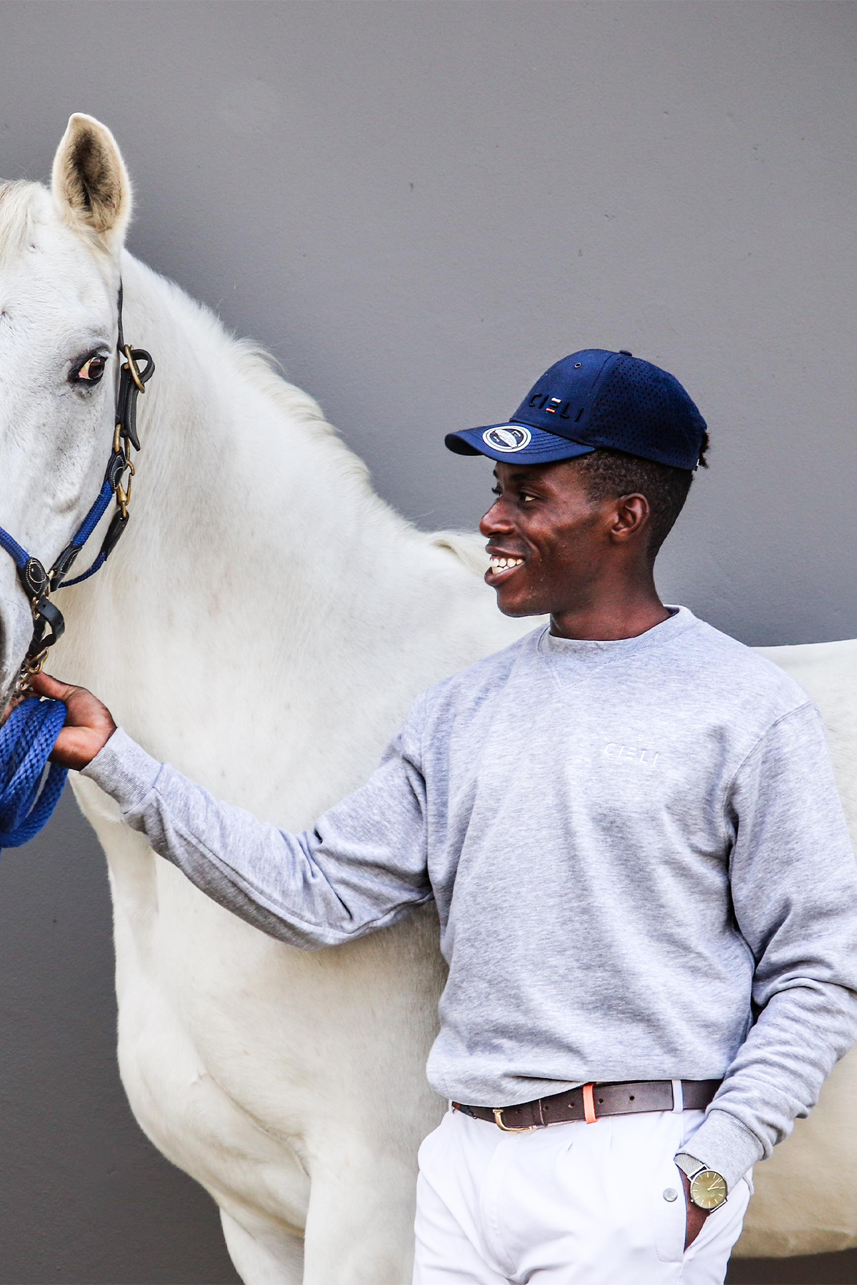 Man wearing a Cieli Equestrian melange grey sweater standing next to a white horse