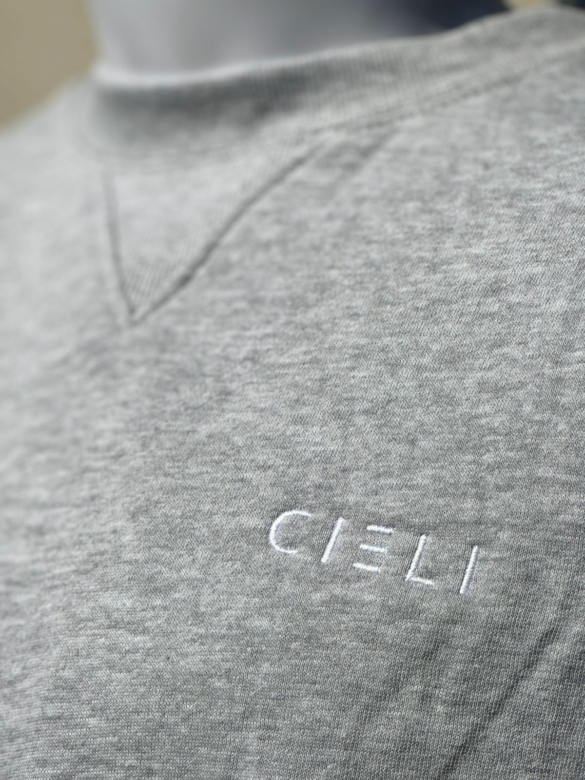 Close of mens melange grey sweater with white Cieli Equestrian embroidery