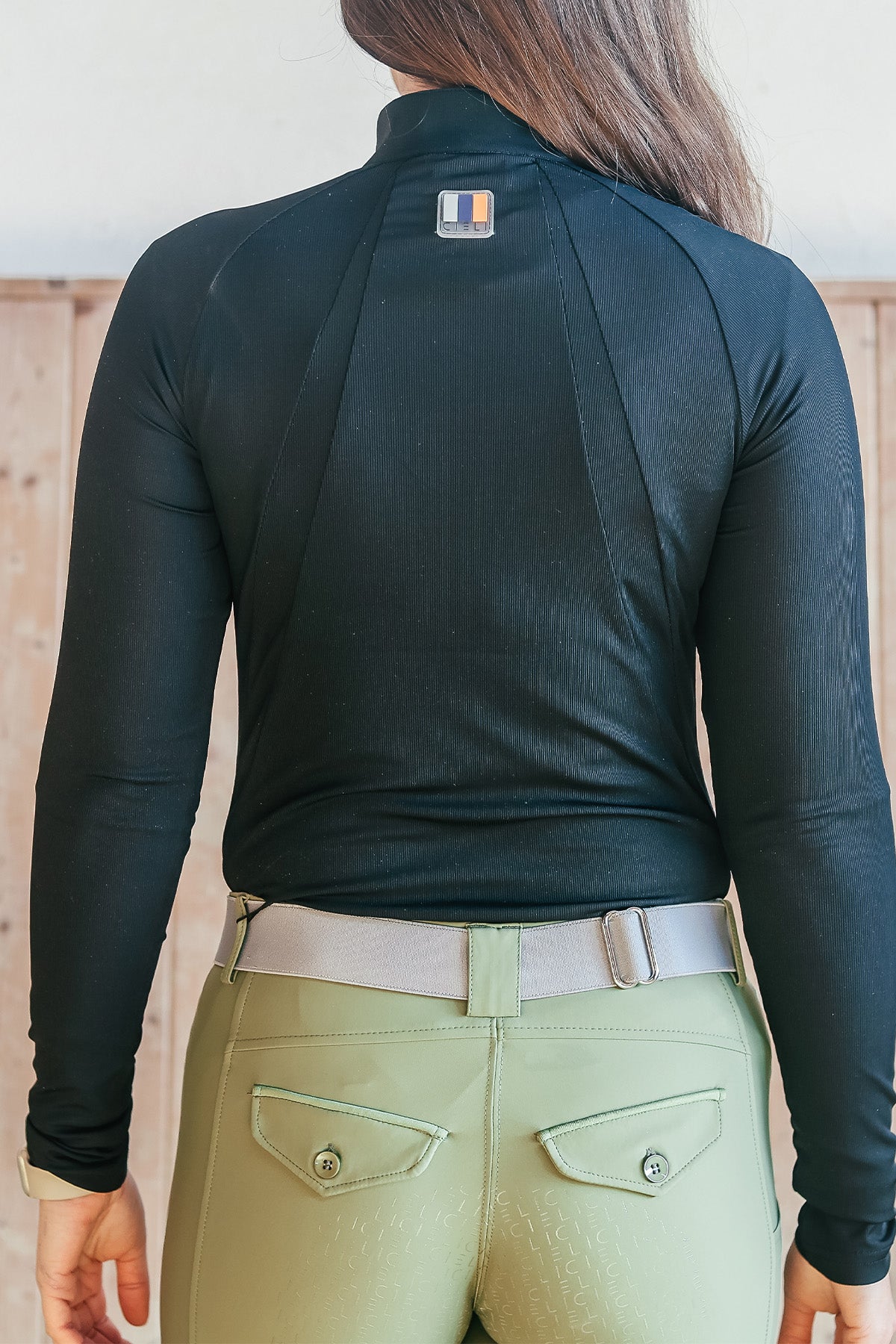 Dark haired girl wearing a cieli equestrian baselayer with uv protection in black