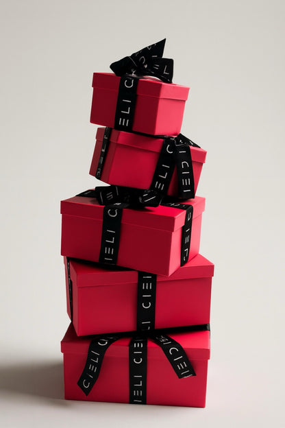 Stack of red gift boxes with black ribbons on a light gray background