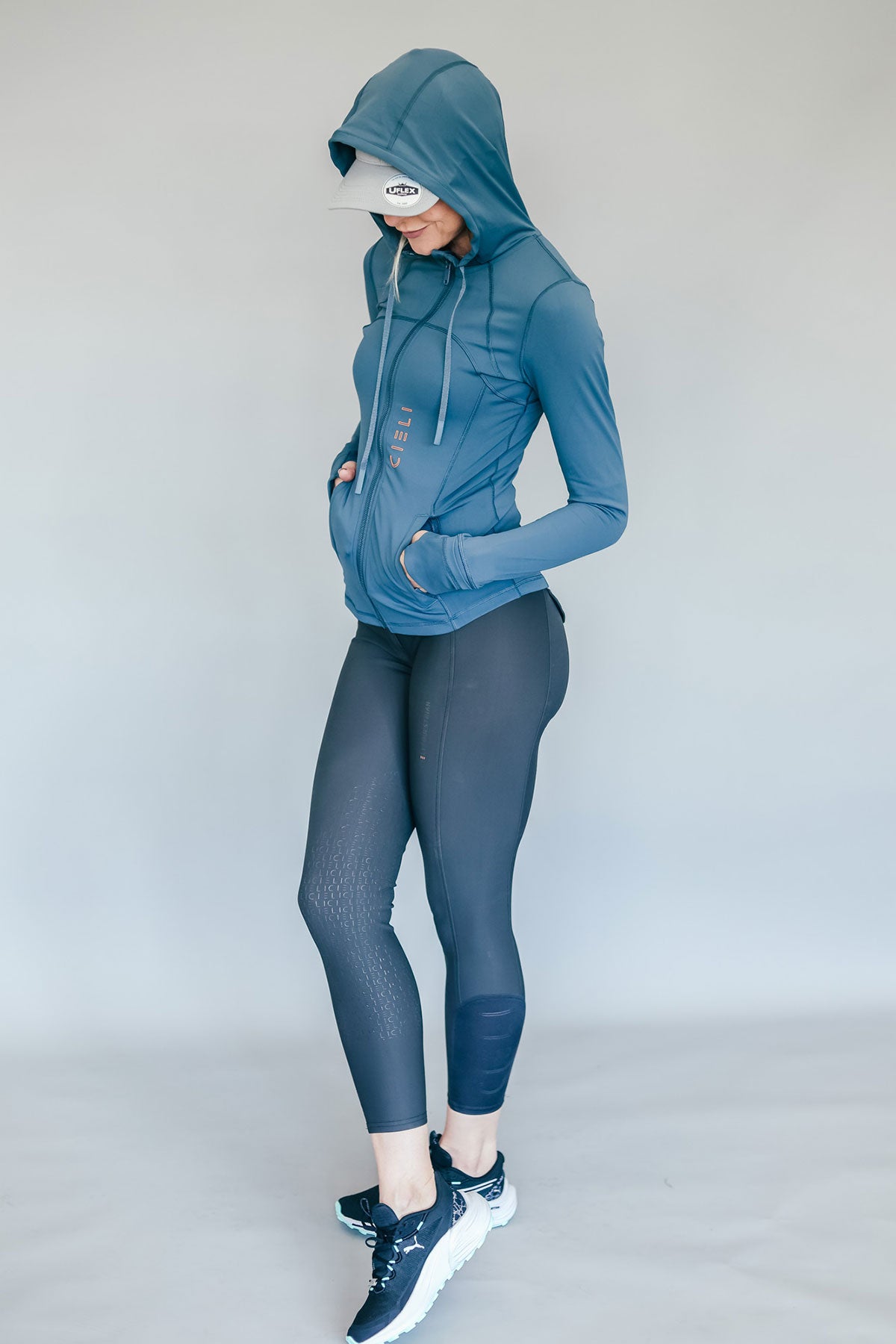 Person wearing a blue athletic outfit with a hood on a plain background