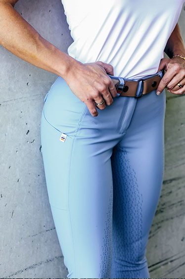 Person wearing light blue leggings with a white top against a concrete wall.