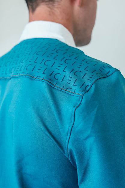 Close-up of a turquoise shirt with 'CIELI' text on the shoulder against a plain background