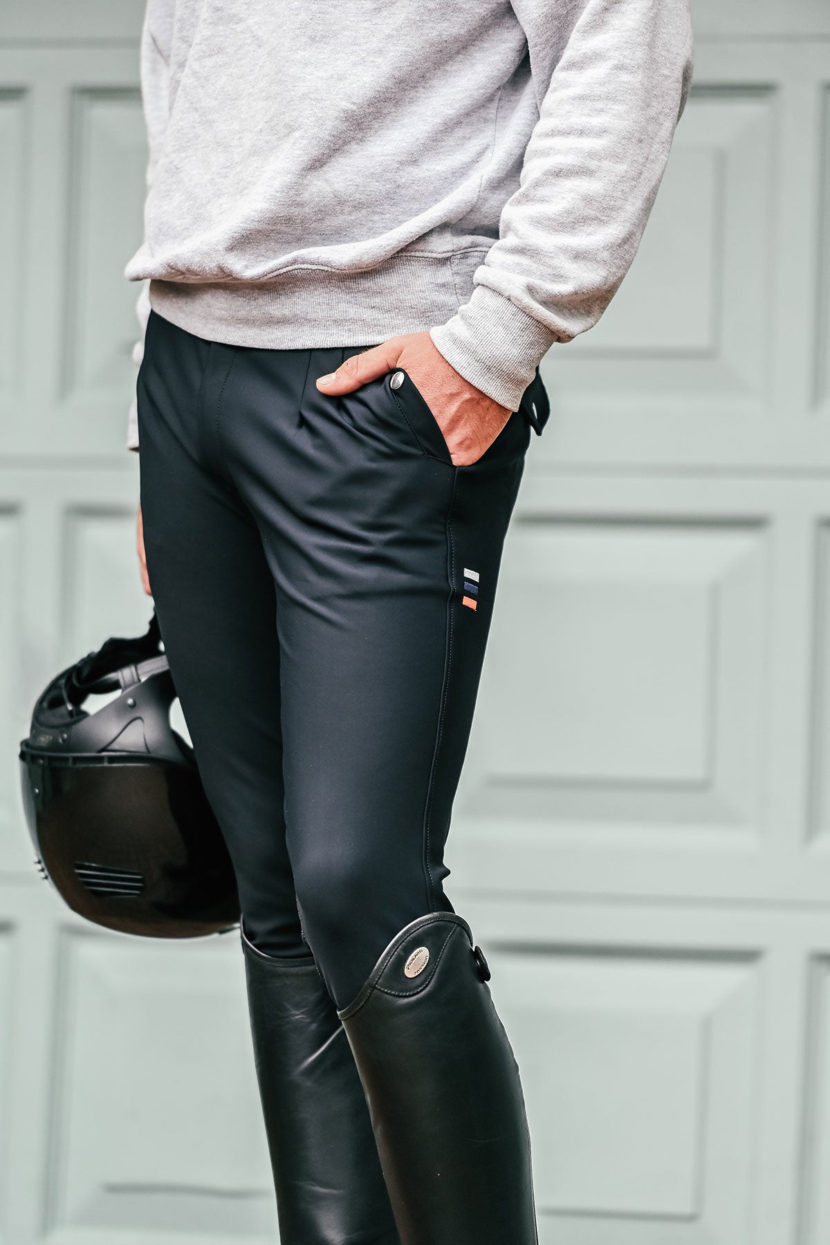 Person wearing black riding pants with knee silicone, standing against a neutral background.