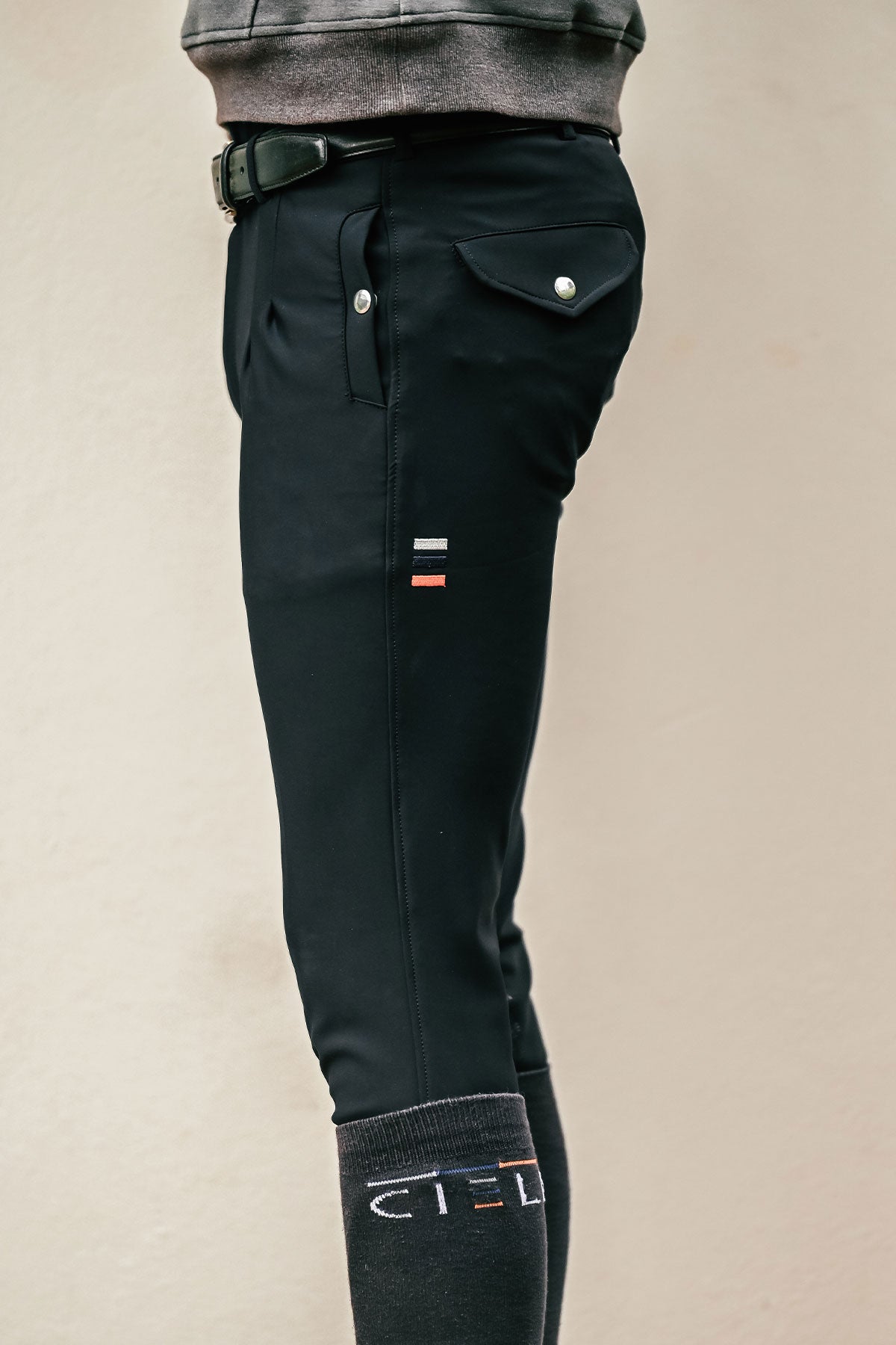 Black riding pants with brand logo on a beige background