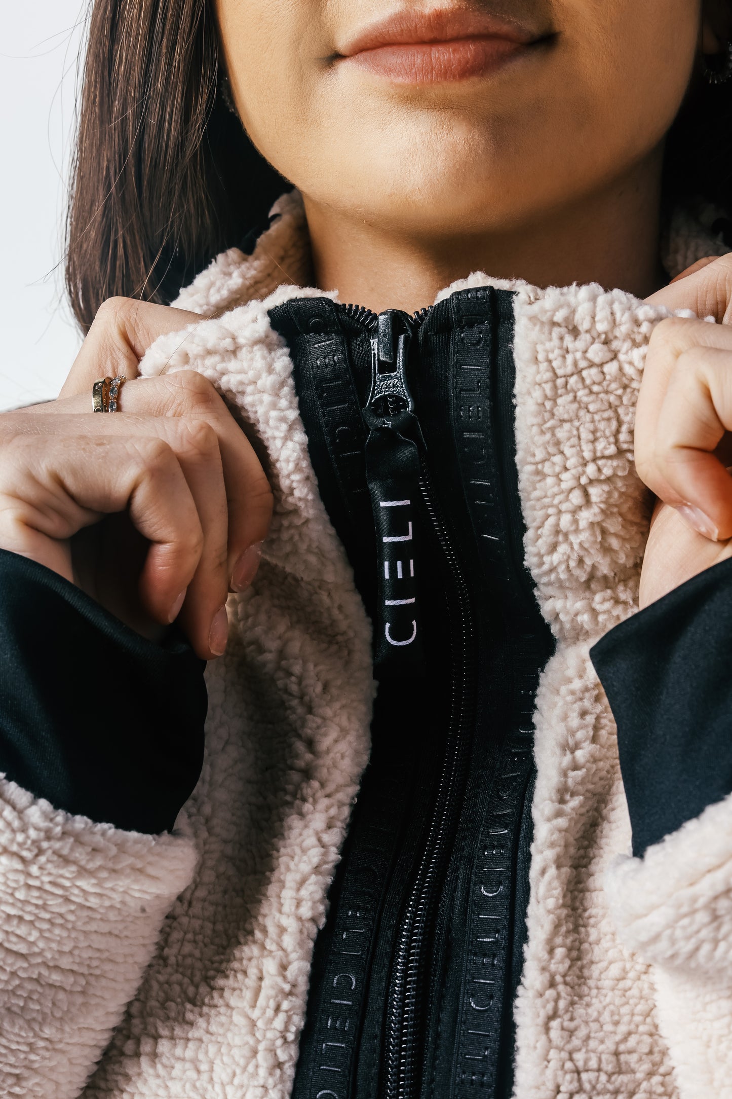 Close-up of a person wearing a beige fleece jacket with a black zipper, focusing on the brand 'Ciel'.