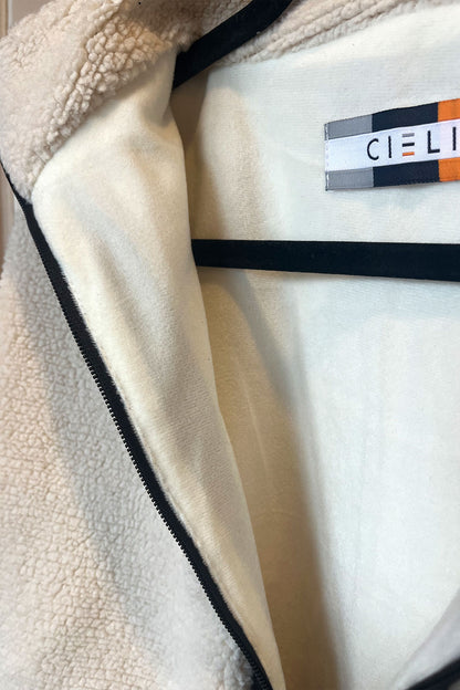 Close-up of a beige fleece jacket with a brand label on a white background